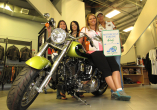 Women sitting on a yellow Harley Davidson Motorcycle holding a motorcycle parking sign